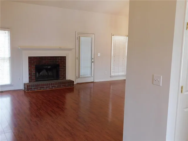 an empty room with wooden floor fireplace and windows