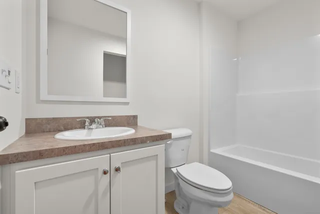 a bathroom with a granite countertop toilet a sink and a mirror