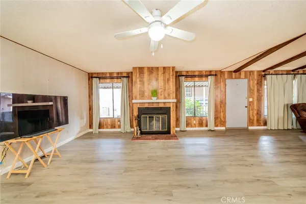 a view of an empty room with wooden floor fireplace and a window