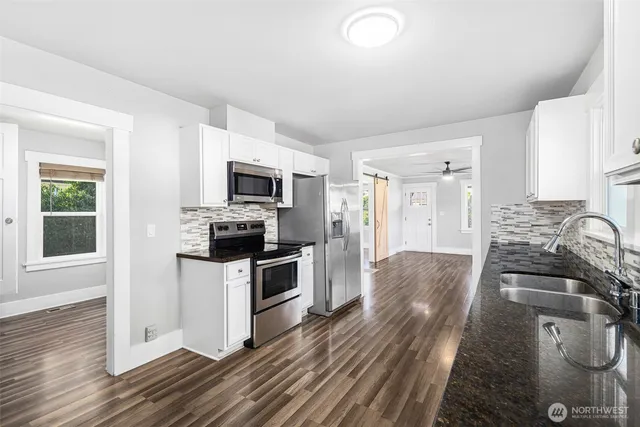 a kitchen with granite countertop a stove top oven a sink dishwasher a dining table and chairs with wooden floor