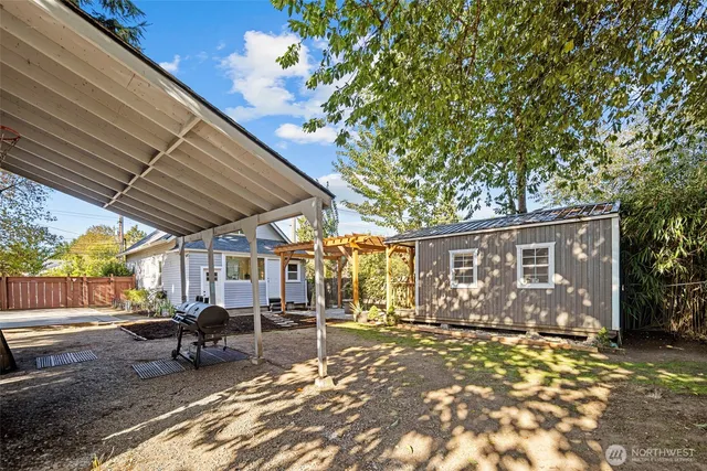 a view of a backyard with table and chairs and a large tree