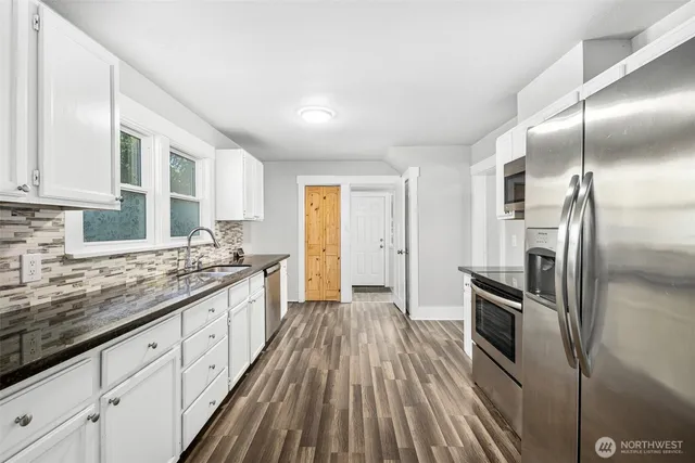 a kitchen with stainless steel appliances granite countertop a refrigerator a sink dishwasher a stove and white countertops with wooden floor