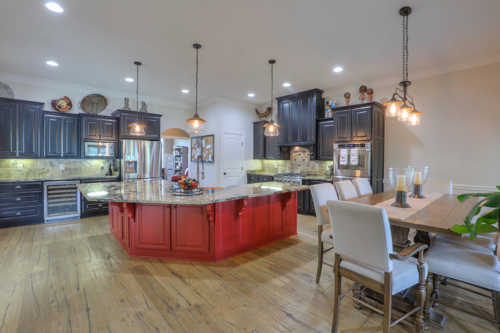 561 Cairo Bend Road Lebanon, TN 37087 - Photo 17 of 29 a kitchen with stainless steel appliances kitchen island granite countertop a stove a refrigerator a sink a dining table and chairs with wooden floor