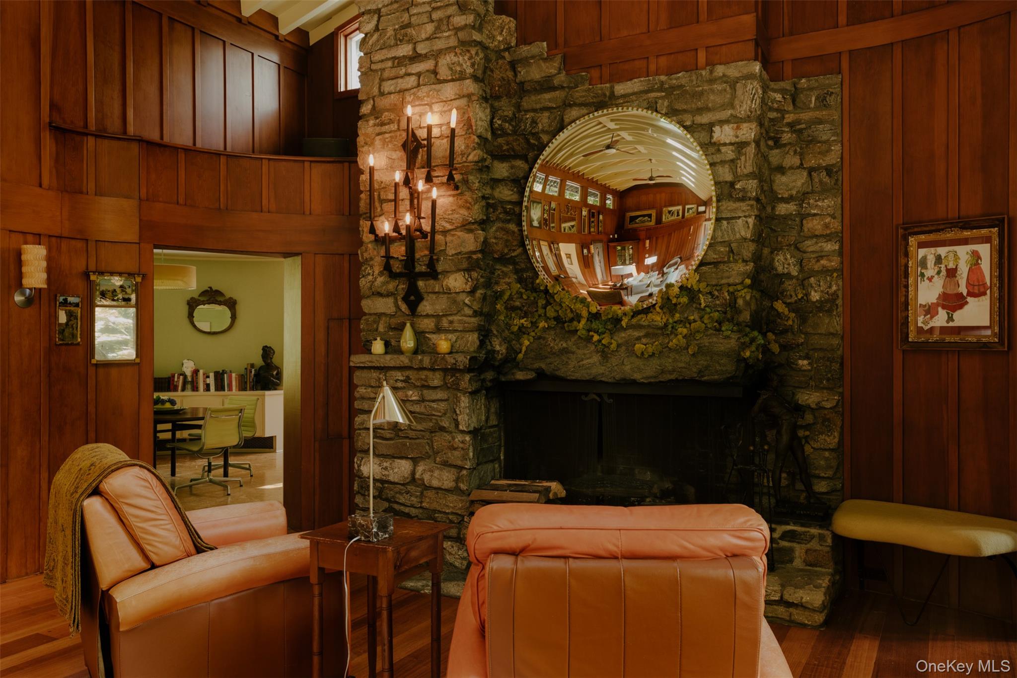 481 Old Albany Post Road Garrison, NY 10524 - Photo 6 of 29 Stone fireplace with a large integrated hearth, featuring a black candelabra sconce and a round mirror