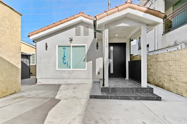 a view of a white house with large windows and a small yard