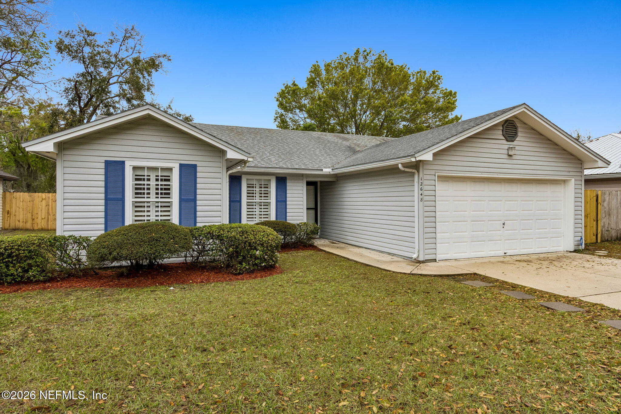a view of a house with a yard plants and large tree
