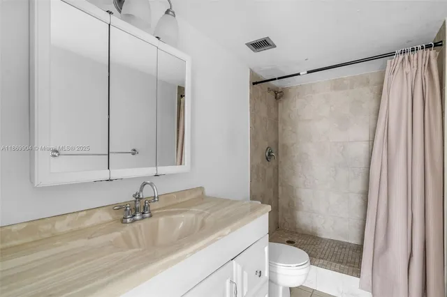a bathroom with a granite countertop sink toilet and shower