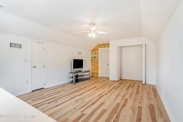 a bedroom with a bed and a flat tv screen on dresser