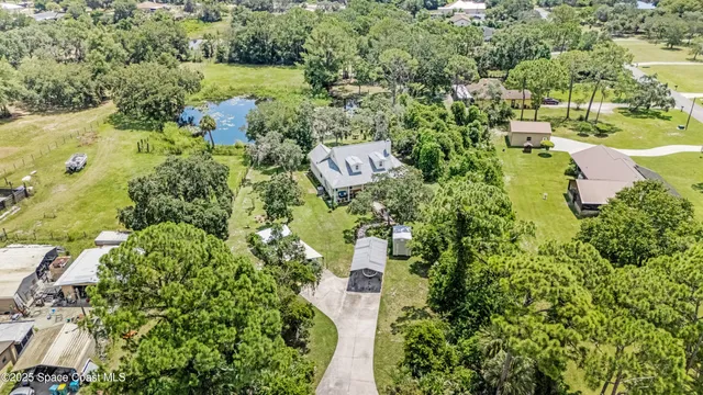 an aerial view of residential house with outdoor space and trees all around