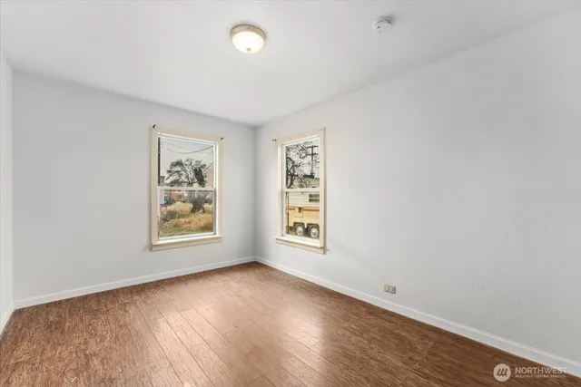 an empty room with wooden floor and window