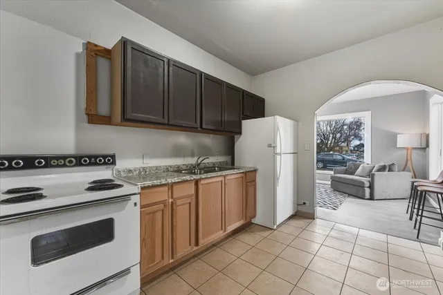 a kitchen with granite countertop a refrigerator stove top oven and white cabinets