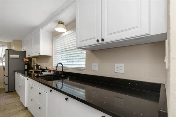 a kitchen with granite countertop white cabinets and a sink