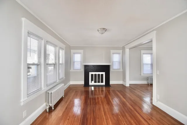 a view of empty room with wooden floor and fireplace