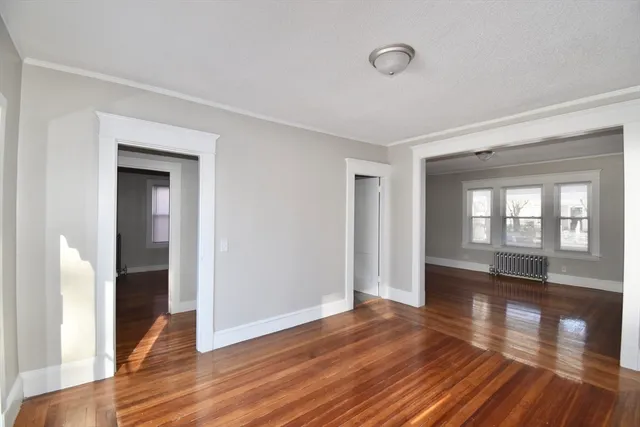 a view of empty room with wooden floor and fan