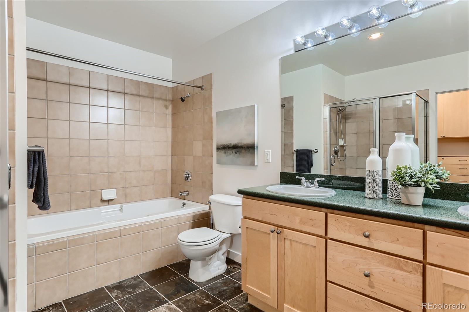 275 South Harrison Street, Unit 602 Denver, CO 80209 - Photo 18 of 33 a bathroom with a granite countertop sink a toilet a mirror a bathtub and shower