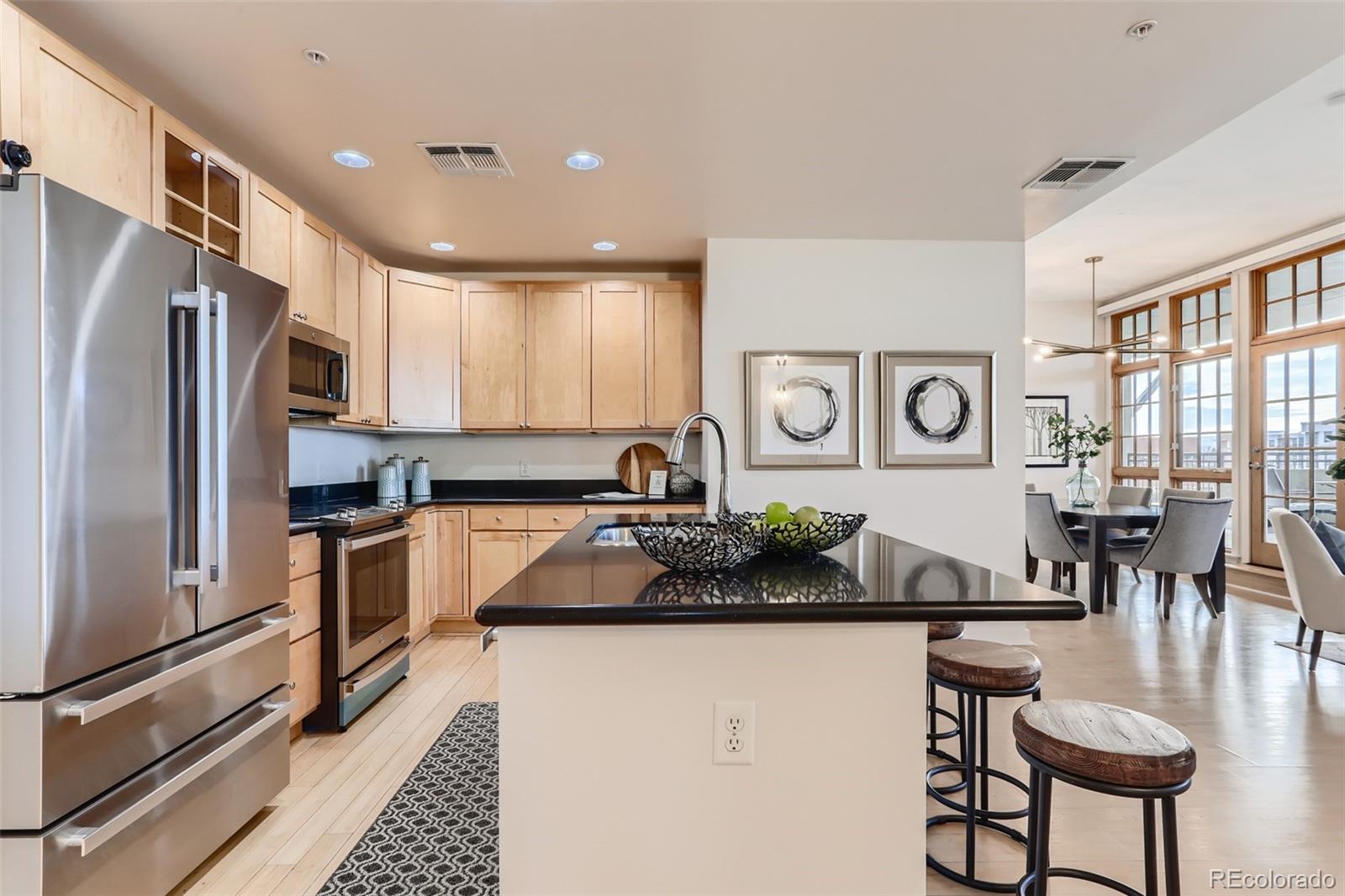 275 South Harrison Street, Unit 602 Denver, CO 80209 - Photo 10 of 33 a kitchen with stainless steel appliances granite countertop a refrigerator and a stove top oven with wooden floor