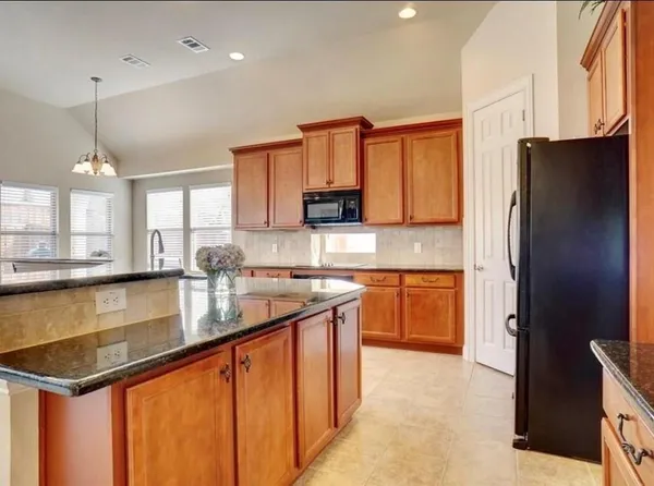 a kitchen with stainless steel appliances granite countertop a refrigerator a stove and a sink with wooden cabinets