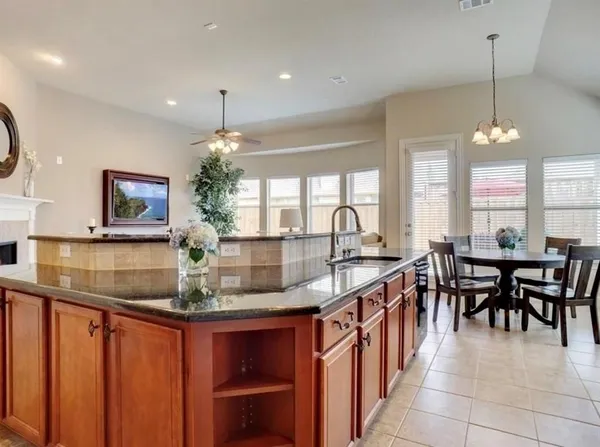 a kitchen with granite countertop a stove a sink a dining table and chairs