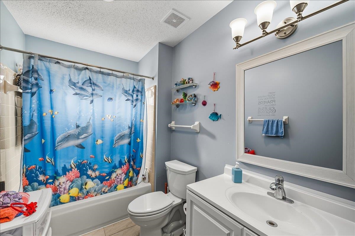 6870 Deerfield Road Bartlett, TN 38135 - Photo 15 of 28 Bathroom featuring vanity, shower / tub combo with curtain, and a textured ceiling