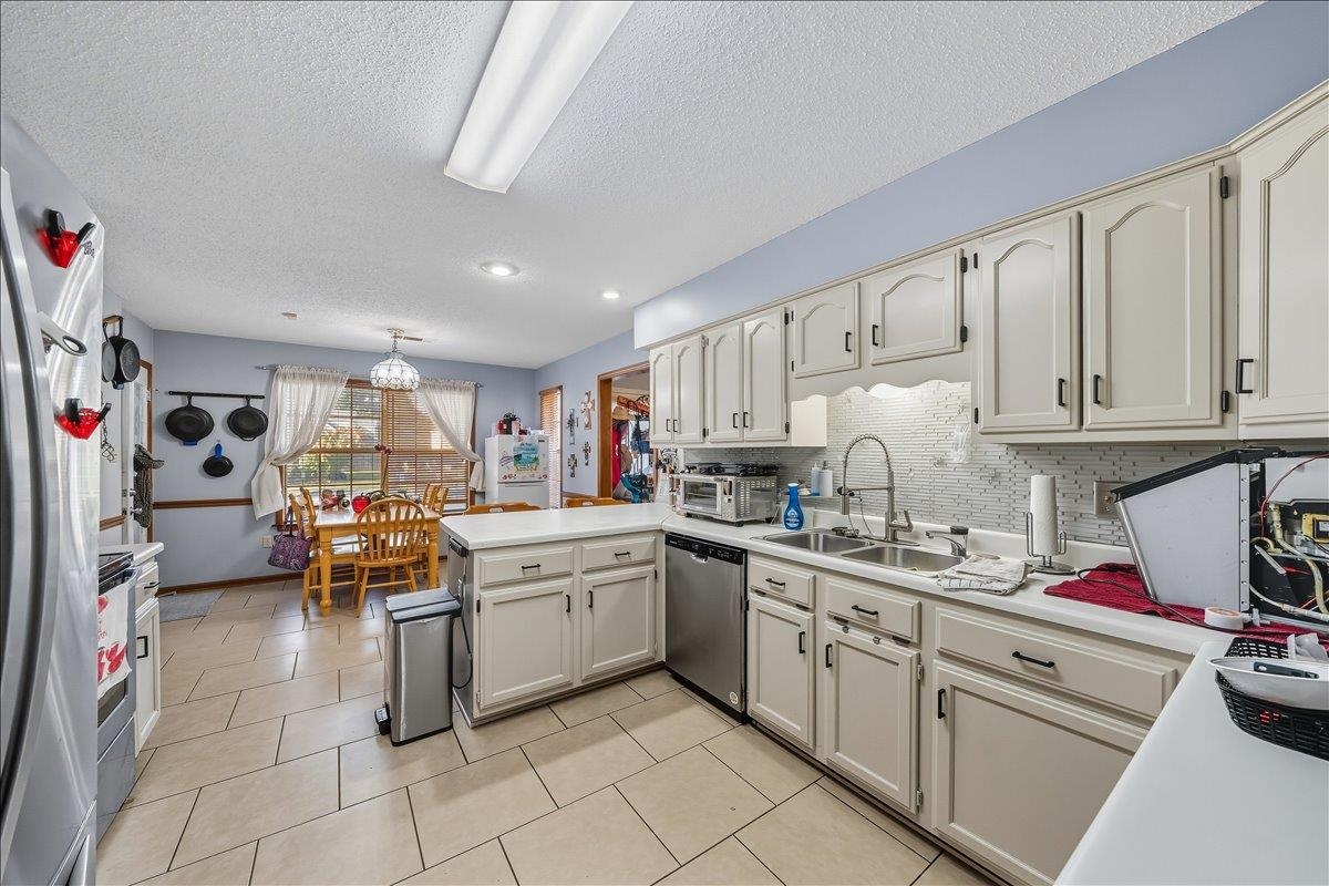 6870 Deerfield Road Bartlett, TN 38135 - Photo 7 of 28 Kitchen featuring light countertops, a peninsula, stainless steel appliances, light tile patterned flooring, and a textured ceiling