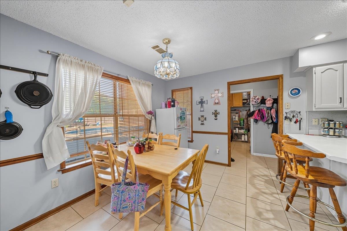 6870 Deerfield Road Bartlett, TN 38135 - Photo 8 of 28 Dining room with a textured ceiling, light tile patterned floors, and hanging lights