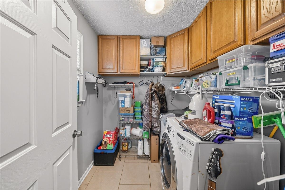 6870 Deerfield Road Bartlett, TN 38135 - Photo 9 of 28 Laundry area with a textured ceiling, washing machine and dryer, cabinet space, and light tile patterned floors