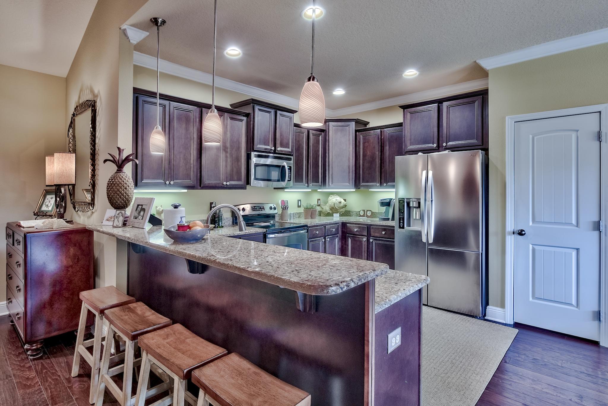 386 Pin Oak Loop Santa Rosa Beach, FL 32459 - Photo 14 of 47 a kitchen with stainless steel appliances granite countertop a refrigerator a sink dishwasher a dining table and chairs with wooden floor