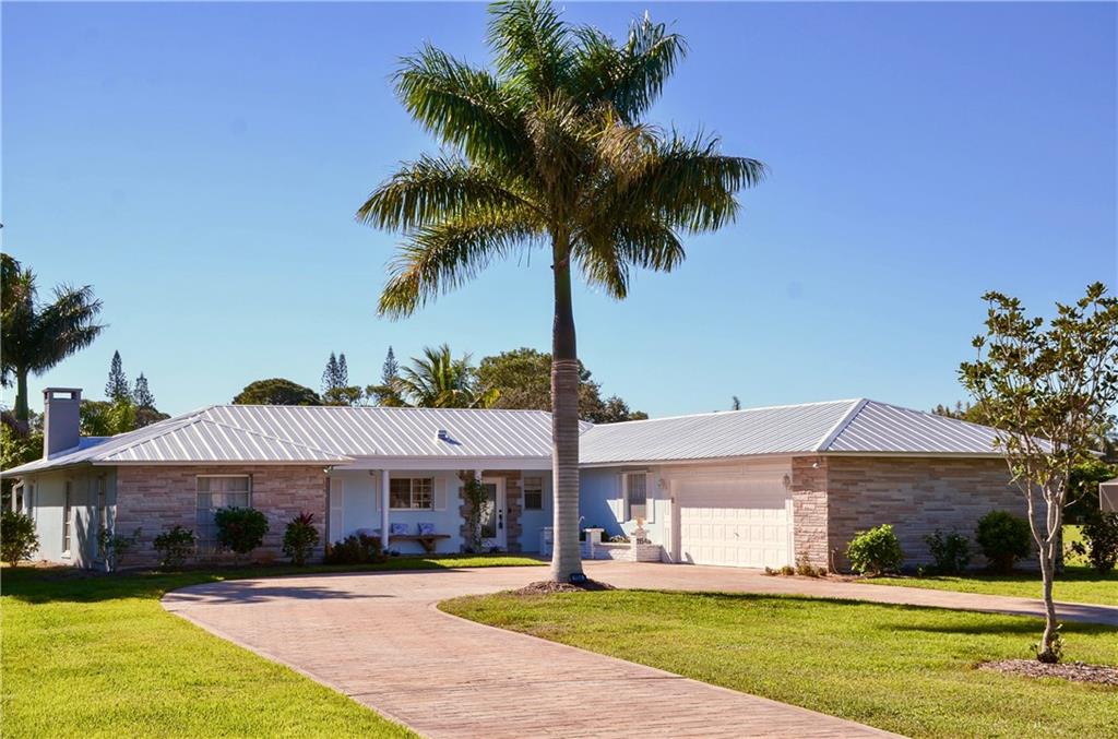 1154 Northwest Spruce Ridge Drive Stuart, FL 34994 - Photo 5 of 43 a front view of a house with garden and trees