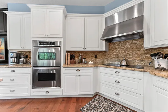 a kitchen with stainless steel appliances granite countertop a sink a stove and a wooden floors