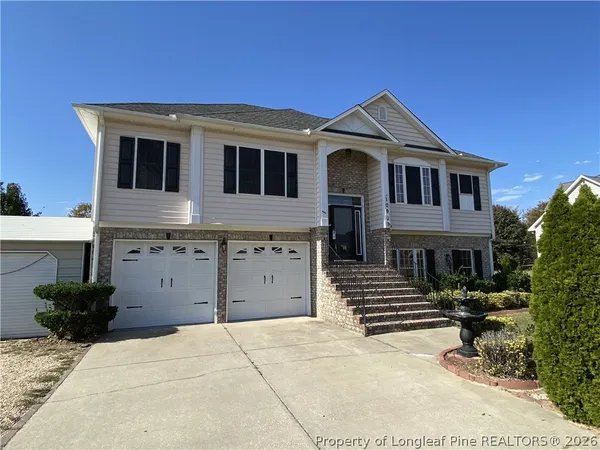 a view of a house with backyard and trees in the background