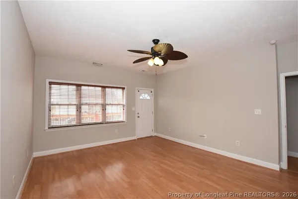a view of empty room with wooden floor and fan