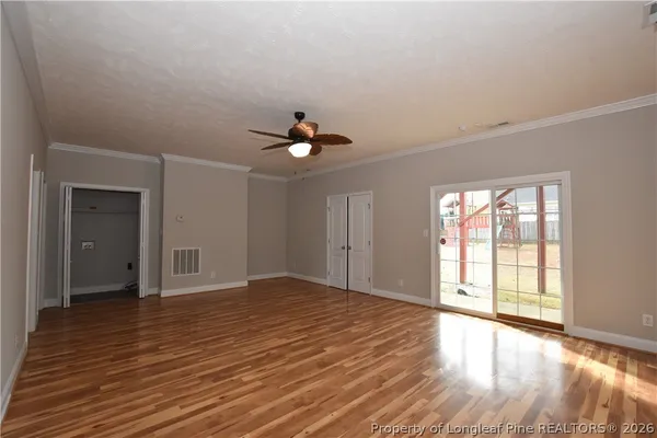 a view of an empty room with wooden floor and a window