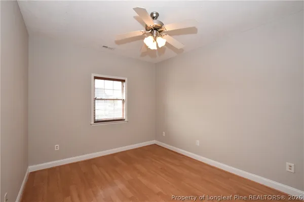 an empty room with wooden floor fan and window