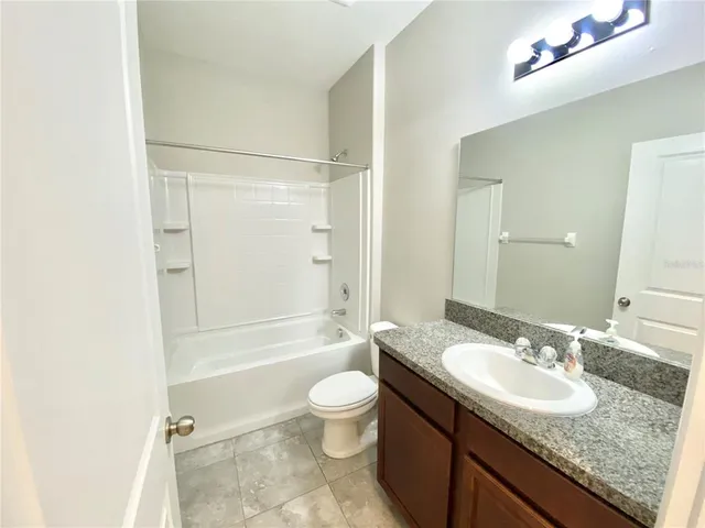 a bathroom with a granite countertop sink toilet mirror and shower