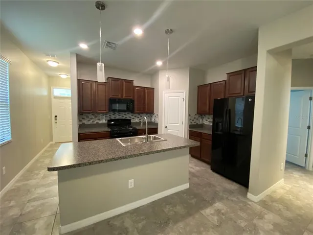 a kitchen with stainless steel appliances granite countertop a refrigerator a stove a sink and a oven