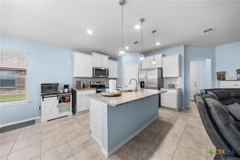 a large kitchen with stainless steel appliances kitchen island granite countertop a sink and cabinets