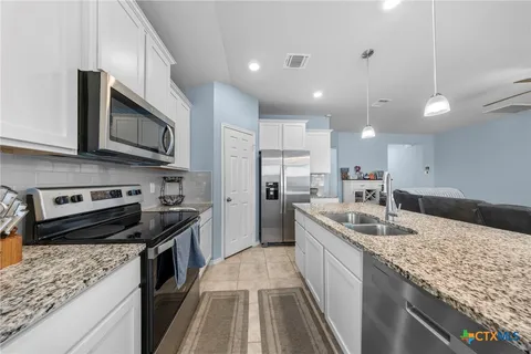 a kitchen with stainless steel appliances granite countertop a sink a stove top oven and cabinetry