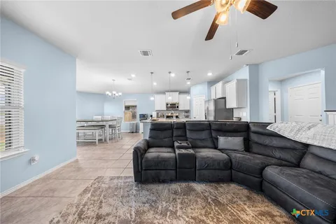 a living room with furniture a flat screen tv and kitchen view
