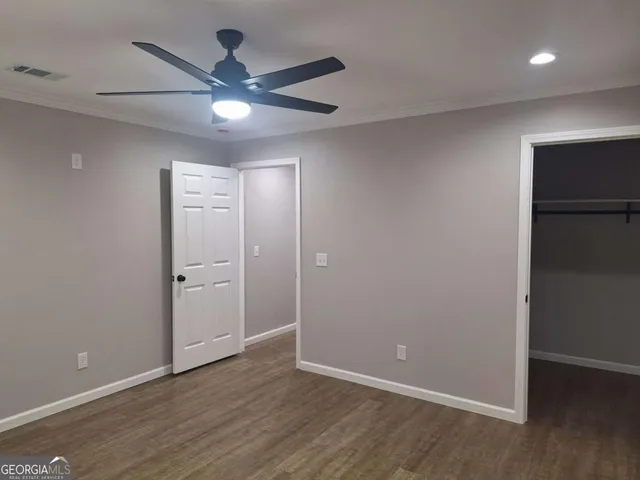 an empty room with wooden floor and a ceiling fan