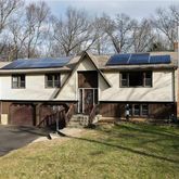 a front view of a house with yard and trees in the background