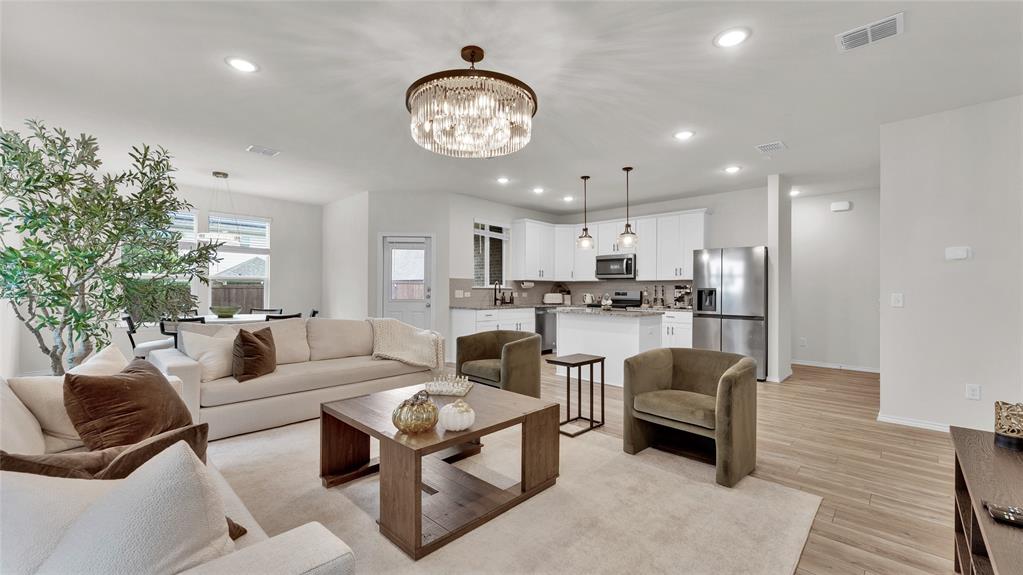 707 Indigo Road Princeton, TX 75407 - Photo 2 of 29 Open-concept living space featuring a contemporary chandelier, recessed lighting, and wood-finish flooring