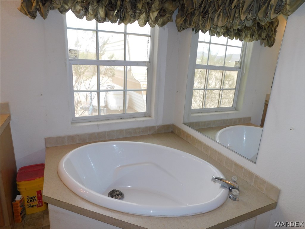 4810 Eloy Road Golden Valley, AZ 86413 - Photo 33 of 35 a bathroom with a tub a window and a shower