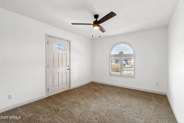 an empty room with a window and a fan