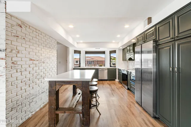 a kitchen with stainless steel appliances granite countertop a refrigerator a stove and a wooden floors