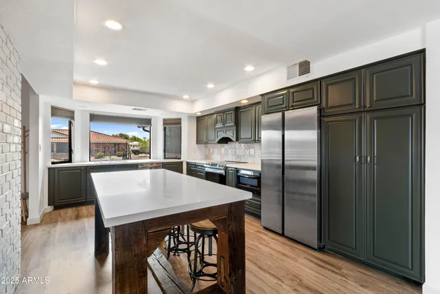 a kitchen with stainless steel appliances granite countertop a refrigerator a stove a sink dishwasher and a refrigerator with wooden floor