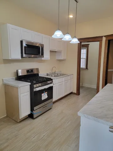 a kitchen with stainless steel appliances a white stove top oven a sink dishwasher and a microwave oven on the kitchen countertops