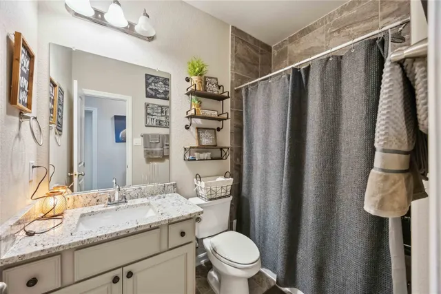 a bathroom with a granite countertop sink toilet and shower