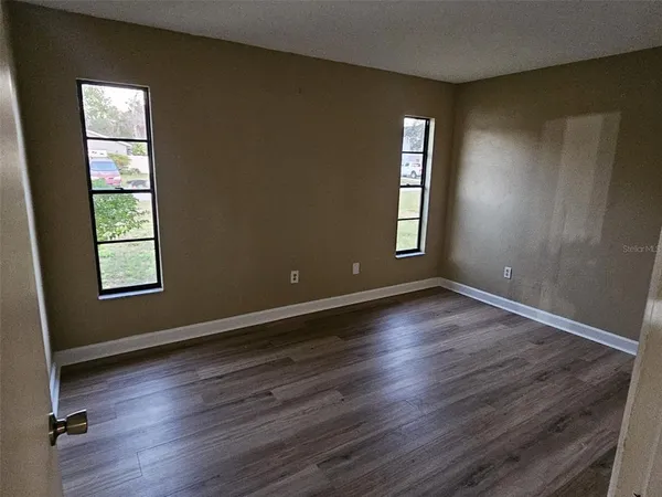 an empty room with wooden floor and windows