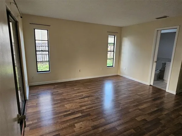 an empty room with wooden floor and windows