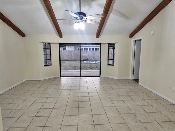a view of empty room with window and chandelier fan